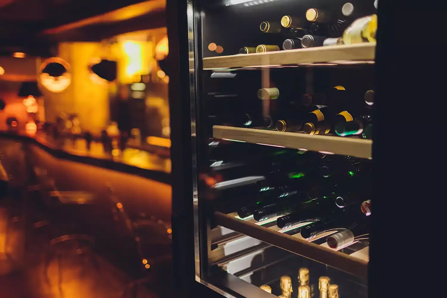 Wine bottles being stored in a wine fridge.
